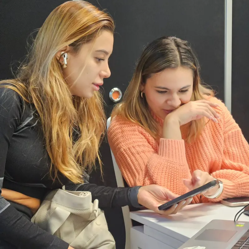 Dos estudiantes revisando contenido en el celular durante una sesión presencial