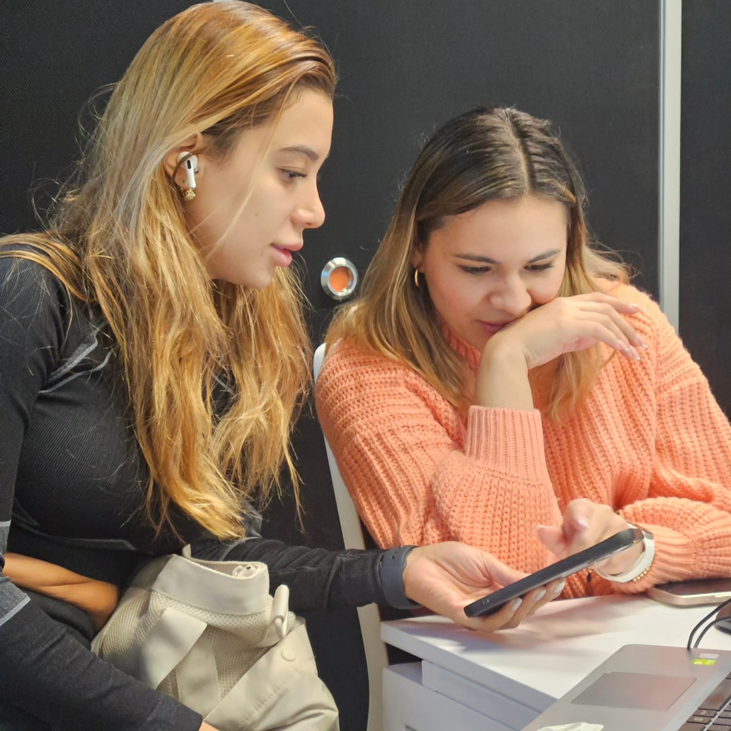 Dos estudiantes revisando contenido en el celular durante una sesión presencial